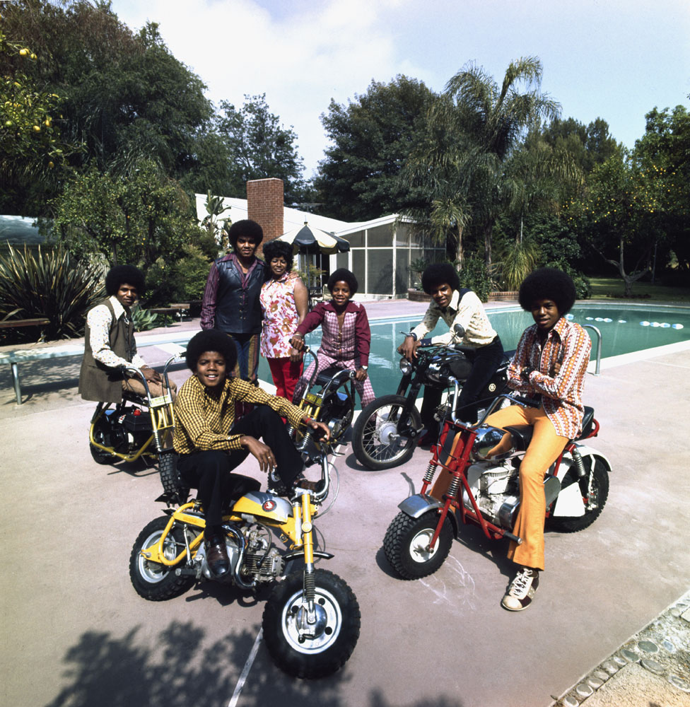The Jacksons (clockwise left to right: Jackie, Marlon, Tito, Jermaine, and Michael) join parents Joe and Katherine in their backyard in Encino, California in 1970. Everyone is on a bike beside their pool.