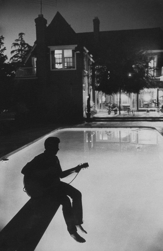 Ricky Nelson sits in shadow on the diving board of his family's pool in Hollywood in 1958.