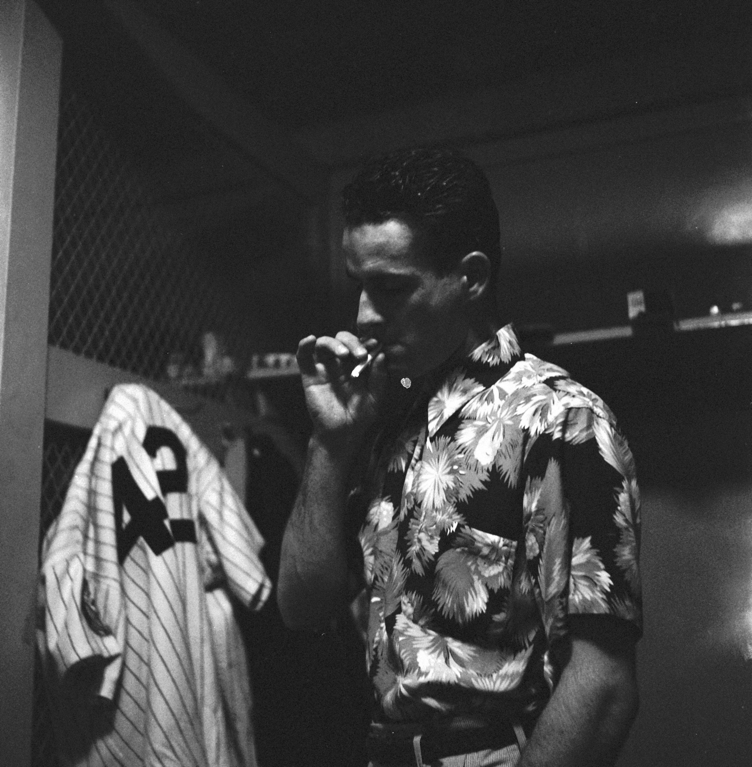 Jerry Coleman takes a long drag from a cigarette in the locker room of Yankee Stadium, New York, New York, April 1952, after learning that he has been called to active military duty for the Korean War. Coleman was a Marine pilot who had previously served in World War II.