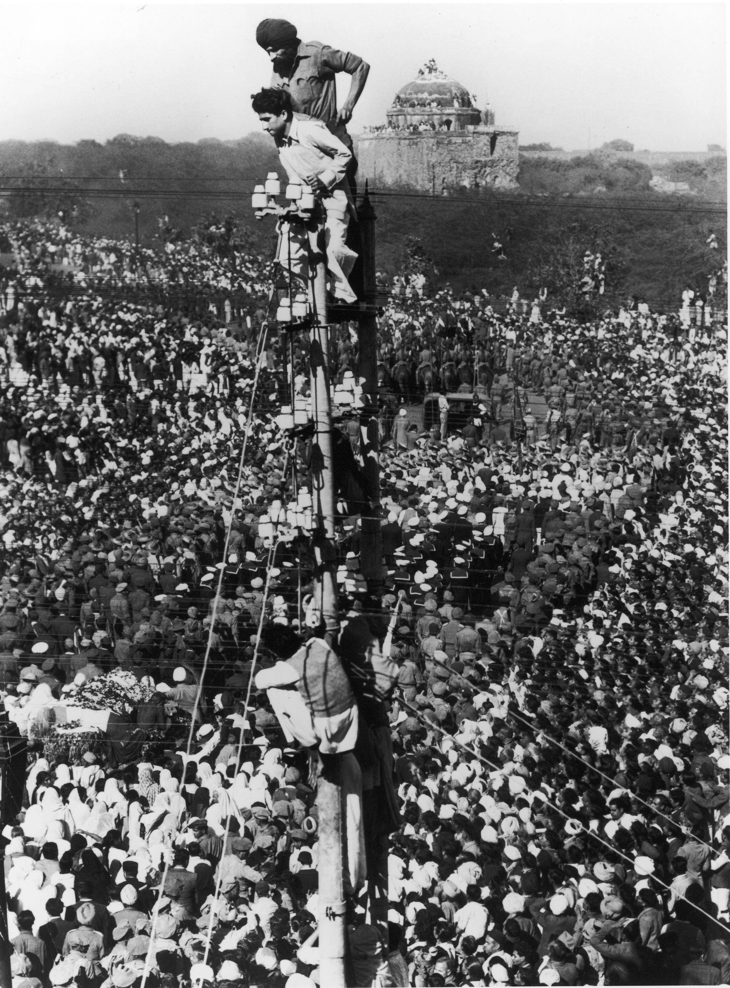 Mourners climb a telephone pole to observe Mohandas Gandhi's funeral procession in January 1948.