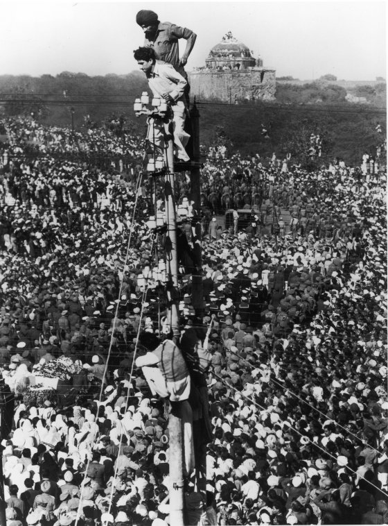 Mourners climb a telephone pole to observe Mohandas Gandhi's funeral procession in January 1948.