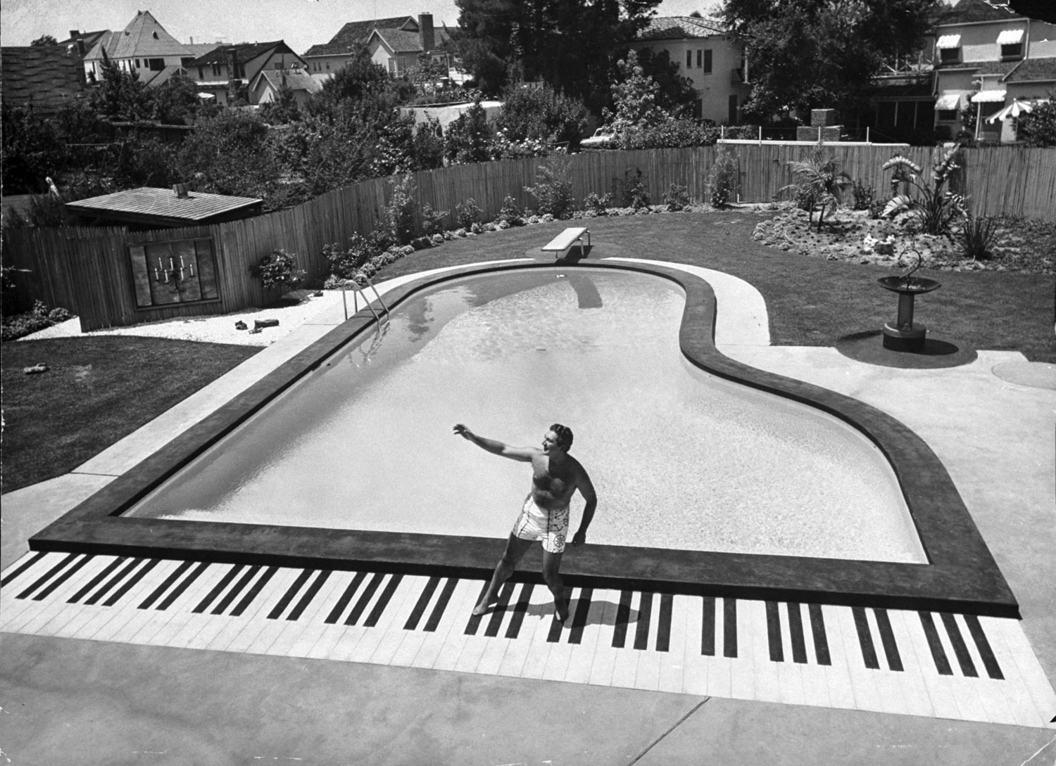 Liberace dances on top of the keys of his piano shaped pool in California in 1954.