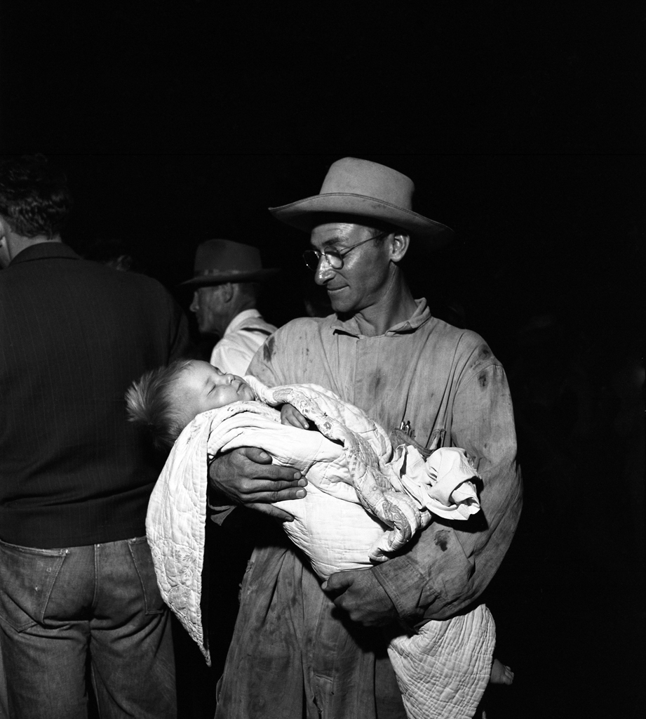 Short Creek raid, Arizona, 1953. This man, reporter Frank Pierson wrote in his notes on the raid, "quietly, smilingly held sleeping child until he was called into courtroom."