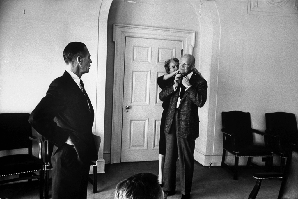 Eisenhower's secretary, Ann Whitman, helps the President with his borrowed tie.