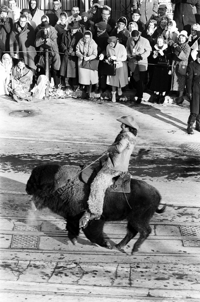 A man dressed like Buffalo Bill rides a bison during John Kennedy's inaugural parade down Pennsylvania Avenue.