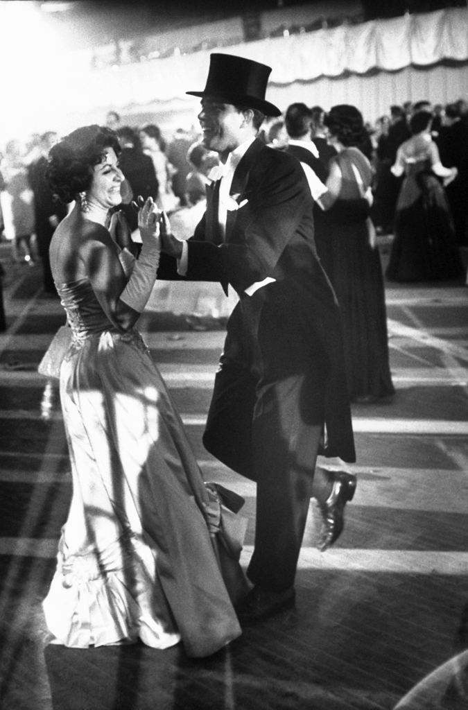 A woman in a gown and a man in a suit with a top hat dance at one of the ball's celebrating John Kennedy's inauguration.