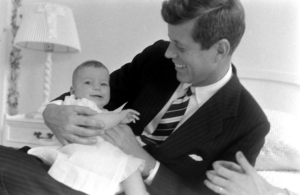 John Kennedy holds his daughter Caroline while lounging on a bed at home in Georgetown, 1958.