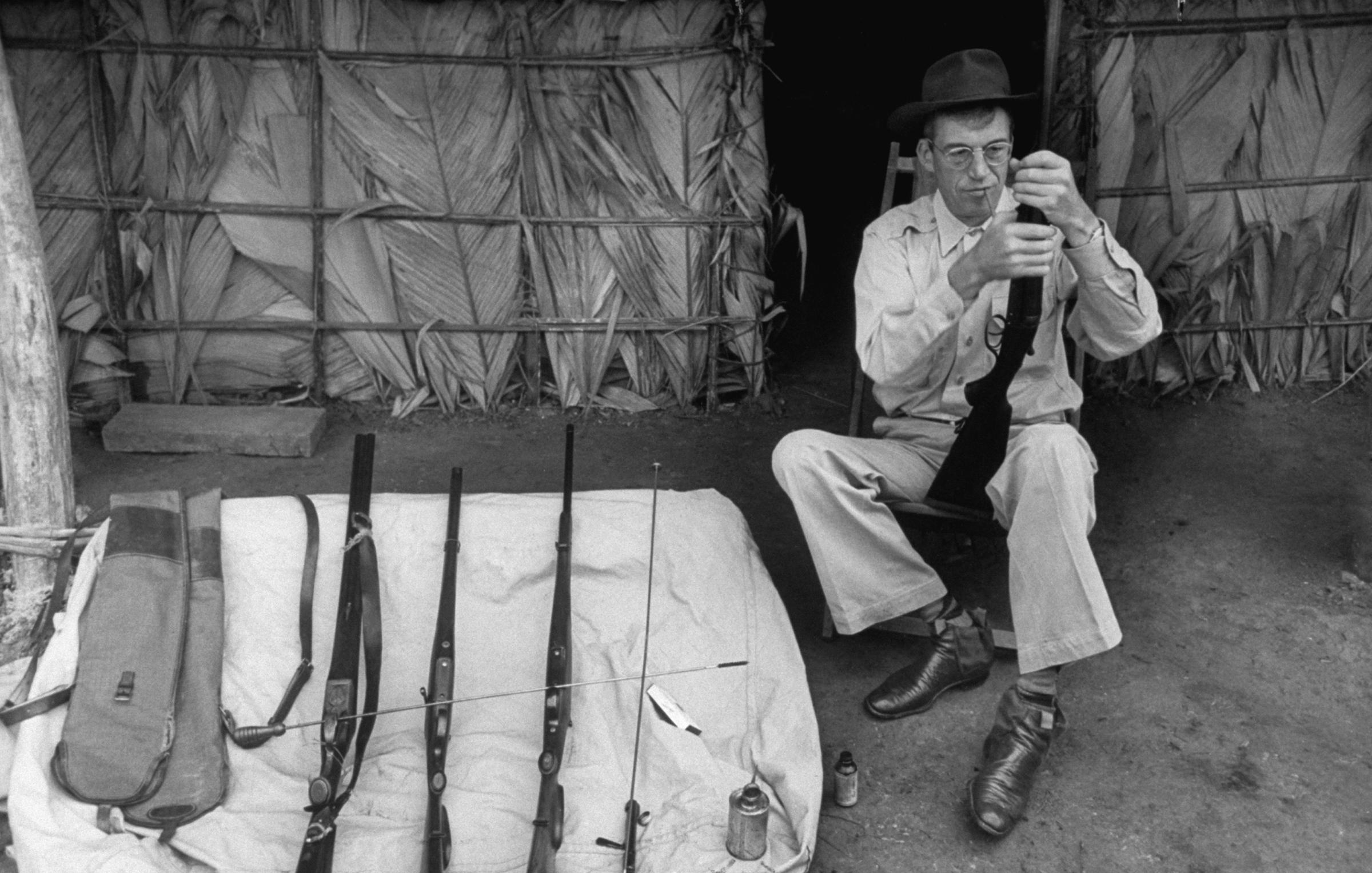 Director John Huston examines one of his rifles during filming of The African Queen, 1951.