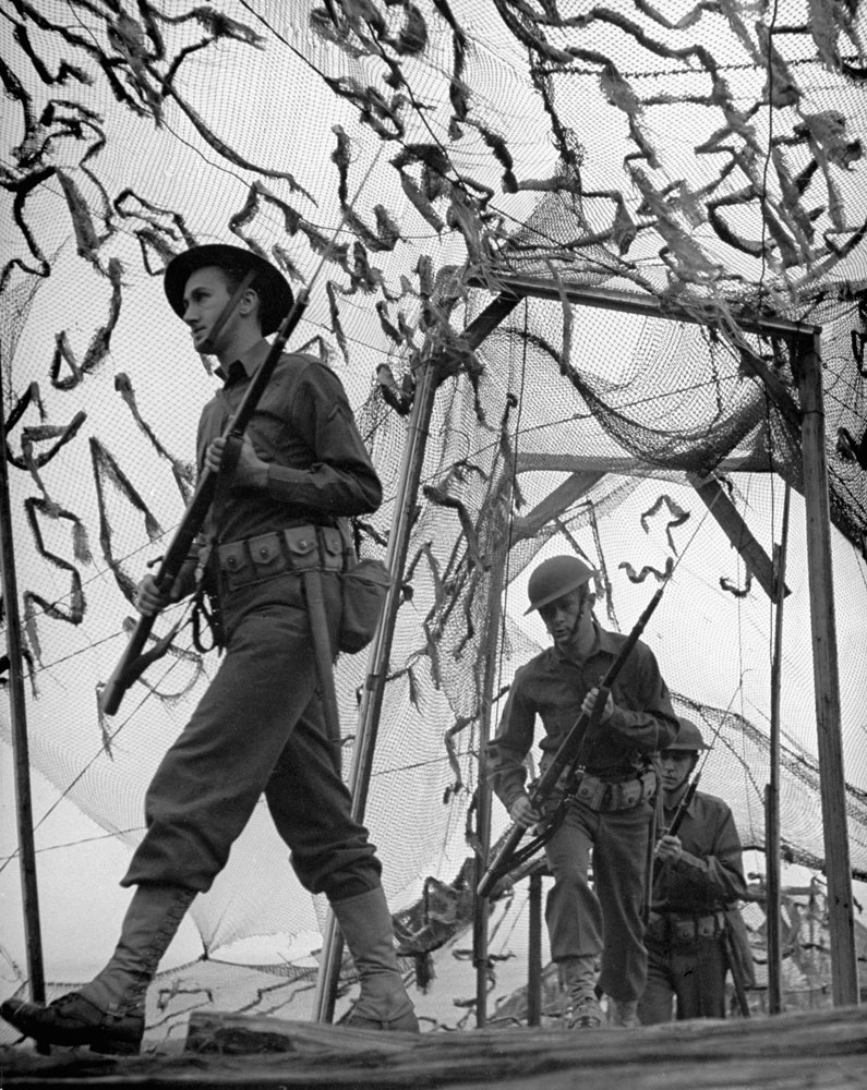 American soldiers drill under camouflage netting, which screens a coastal defense position, in 1942, shortly after the Japanese attack on Pearl Harbor.