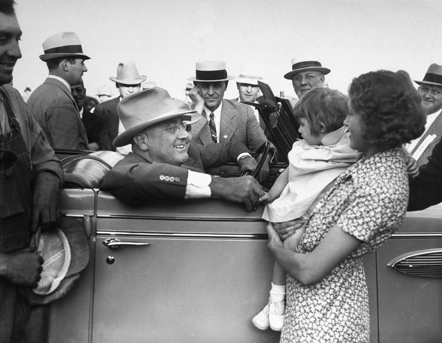 President Franklin D. Roosevelt talks to a young mother while sitting in his car during a trip to the West in 1936.