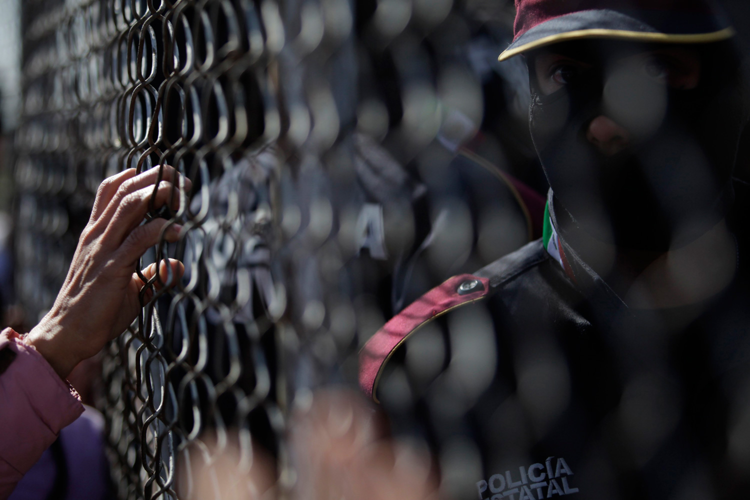 Feb. 19, 2012. A relative of an inmate waits next to a fence for news as a police officer stands guard inside a state prison in Apodaca, on the outskirts of Monterrey, Mexico.