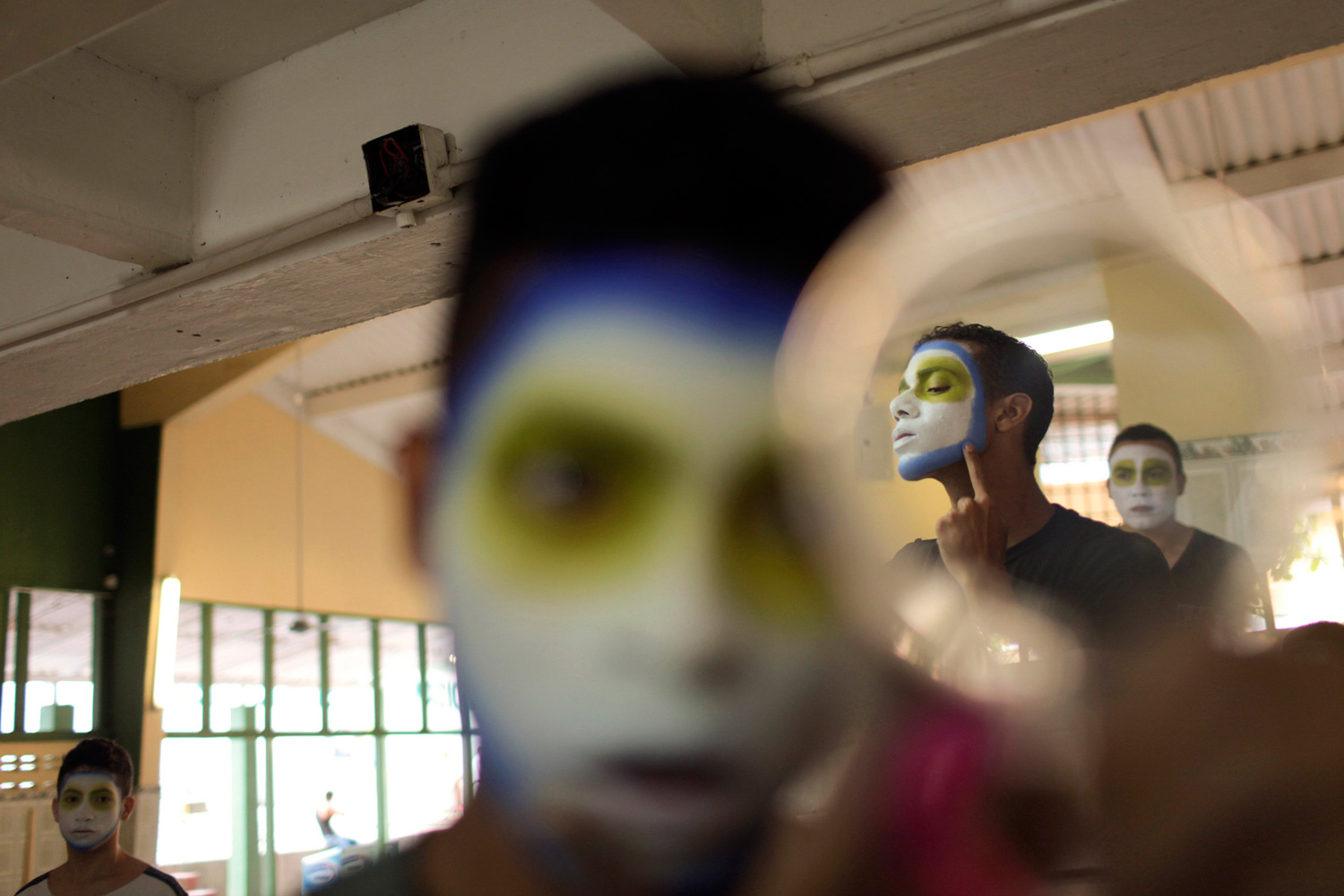 Feb. 18, 2012. A boy with a painted face holds a mirror that reflects other boys, during preparations before a parade as part of the Barranquilla Carnival in Barranquilla, Colombia.
