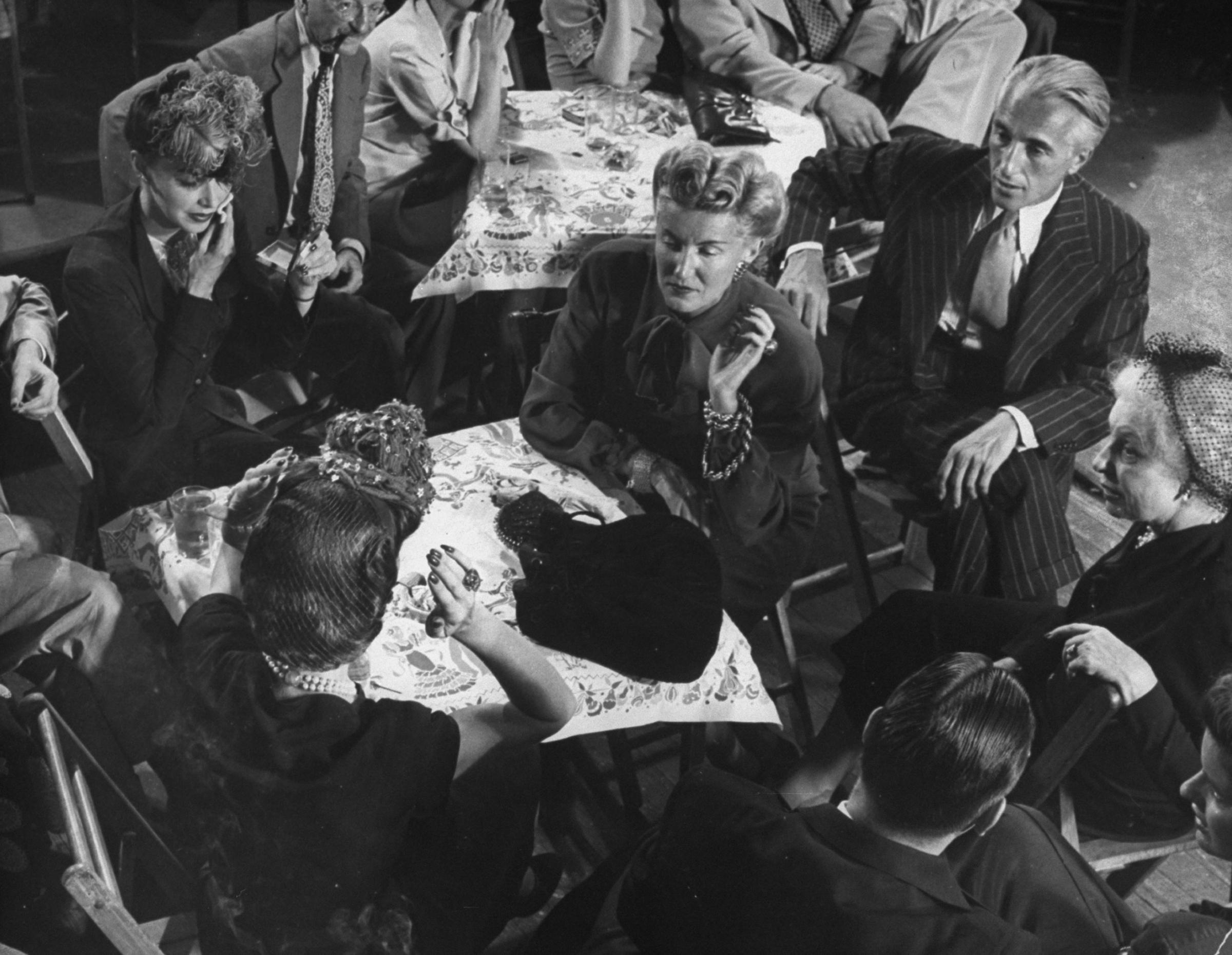 Conde Nast president Iva Patcevitch (in striped suit), Vogue editor-in-chief Edna Woolman Chase (far right, in hat) and other media types hang out at Gjon Mili's studio during a jam session, 1943.