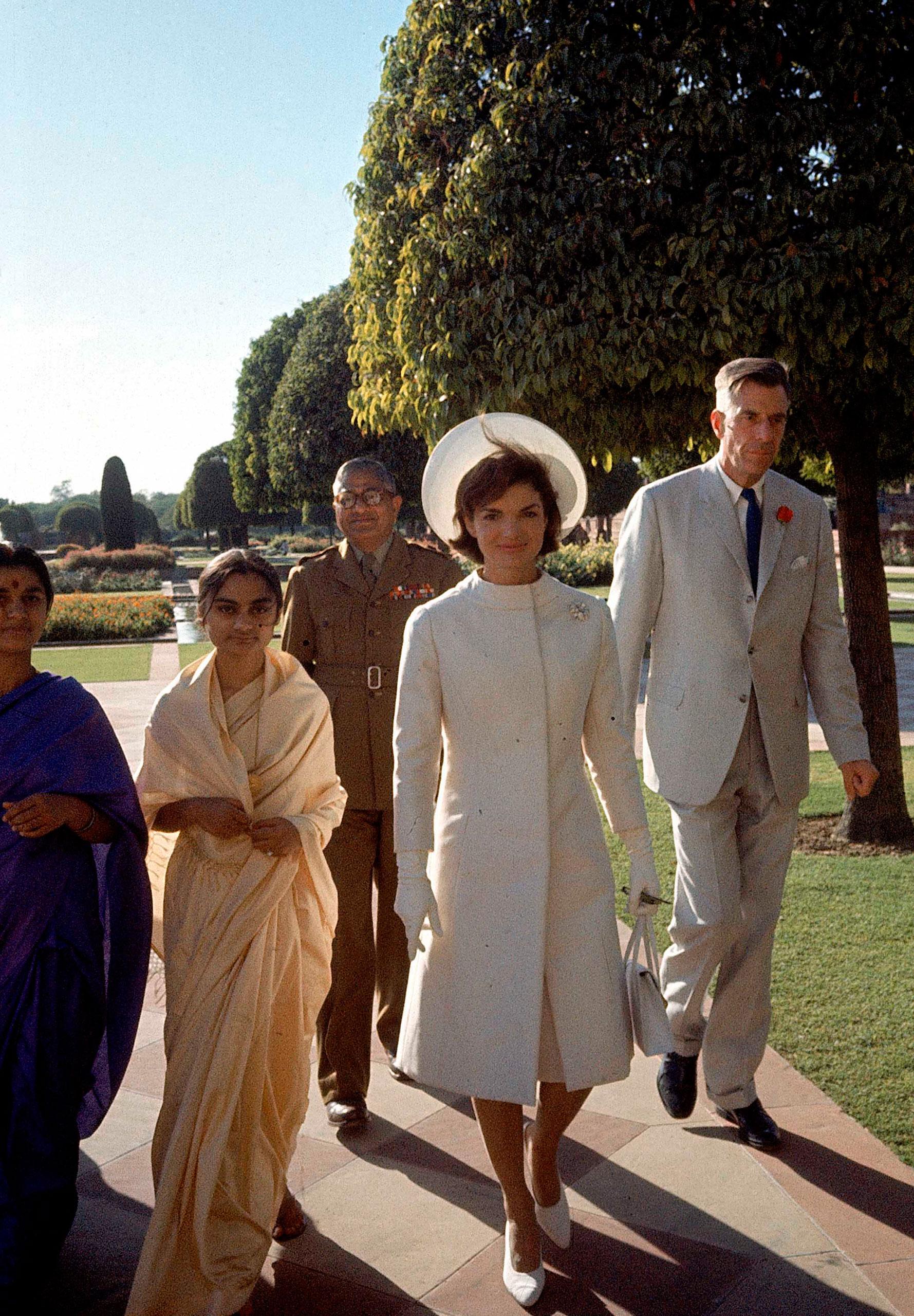 First Lady Jackie Kennedy, center, in a white coat and hat walks with Ambassador John Galbrath, right, in India in 1962.