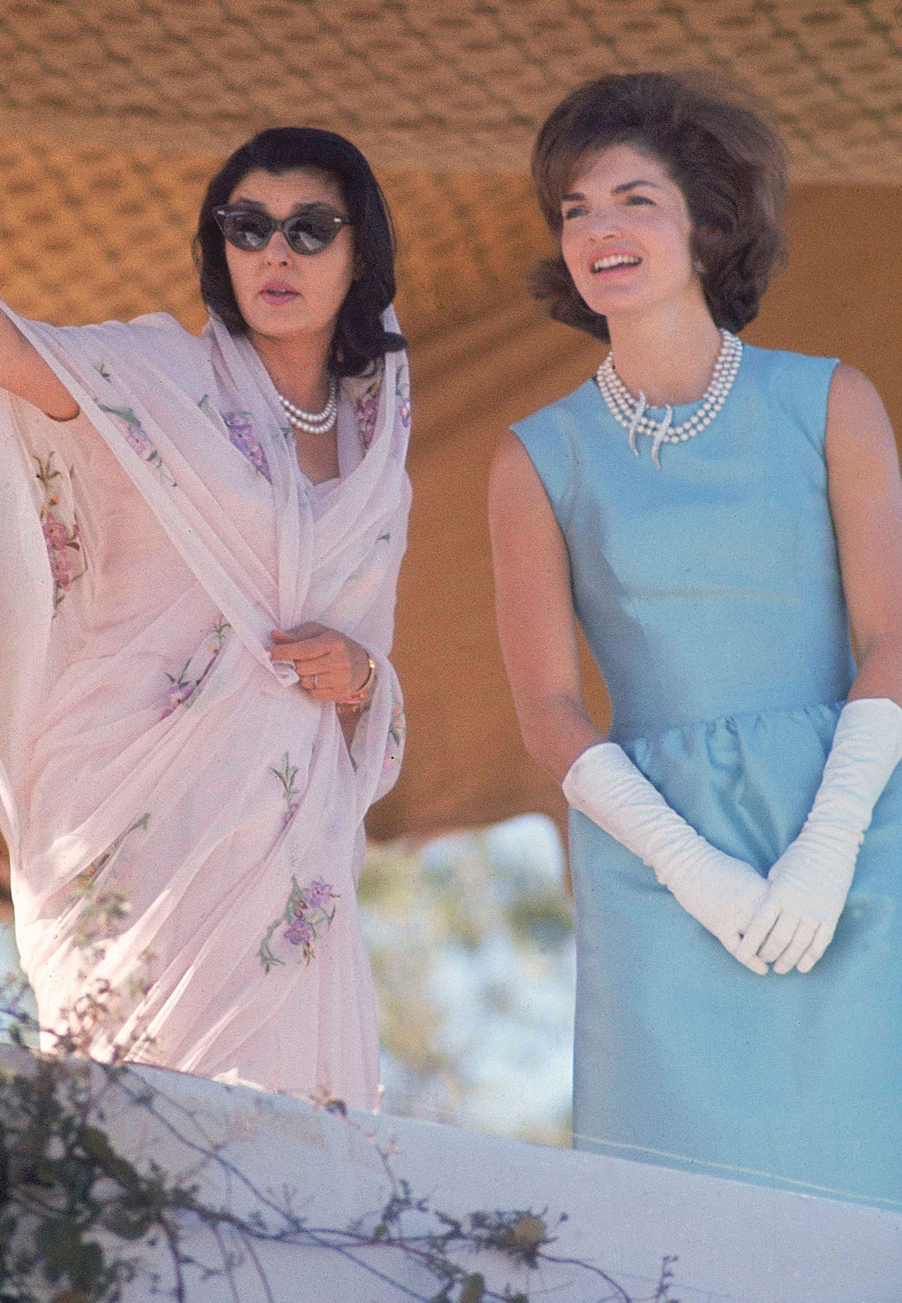First Lady Jackie Kennedy, right, in blue sheath dress and white gloves watches a polo match with Maharani of Jaipur, Gayatri Devi, on a visit to India in March 1962.