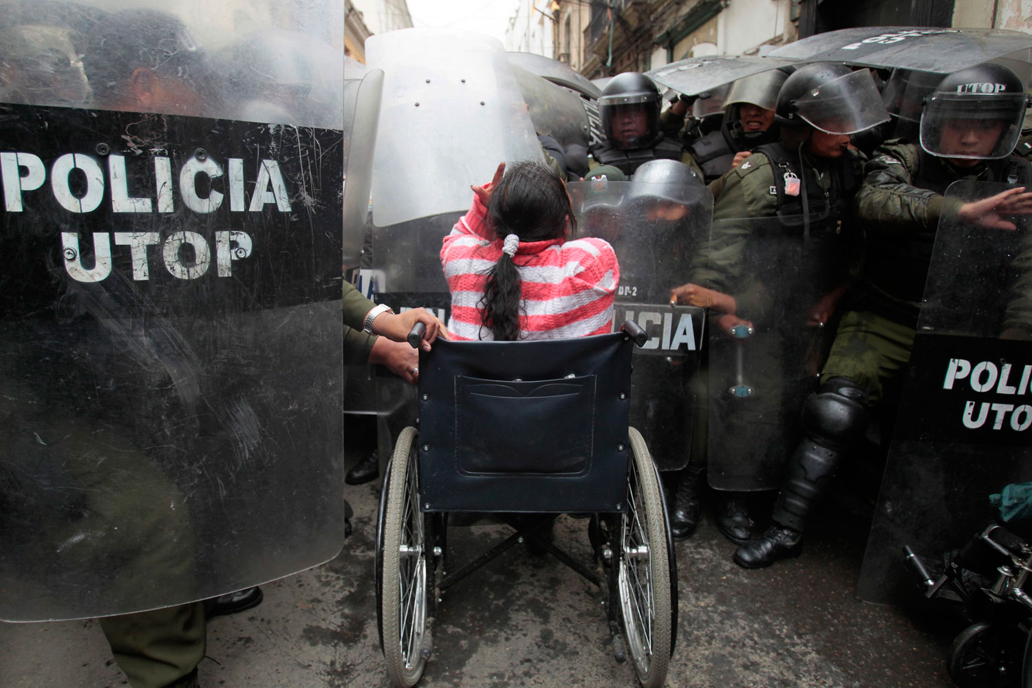 Feb. 23, 2012. A physically disabled woman on her wheelchair clashes with riot police in the centre of La Paz. Hundreds of physically disabled people arrived in La Paz on Thursday after completing a protest march of some 1600 km (994 miles) over a hundred days to demand that Bolivia's government offer support in the form of 3000 bolivianos ($434) payment to each physically disabled Bolivian, according to local media.