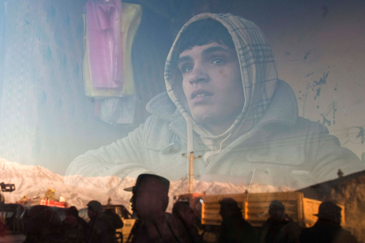 February 24, 2012.  An Afghan boy who works at a bakery watches a protest outside his a window in Kabul. Twelve people were killed on Friday in the bloodiest day yet in protests that have raged across Afghanistan over the desecration of copies of the Muslim holy book at a NATO military base with riot police and soldiers on high alert braced for more violence.