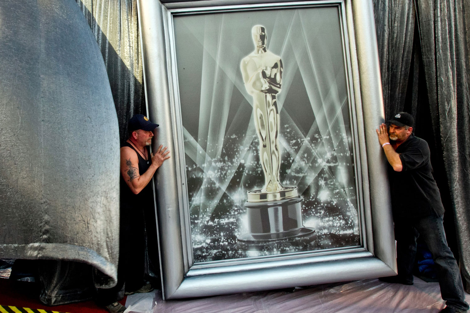 Feb. 23, 2012. International Alliance of Theatrical Stage Employees Union Local 33 Hollywood stage crewmen Shawn Schull, left, and John Shipton move an Oscar frame for the 84th Annual Academy Awards, to be held on Sunday, outside the Kodak Theatre in Los Angeles.