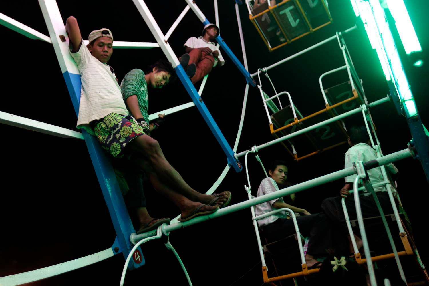 Feb. 22, 2012. Workers stand on a Ferris wheel as they wait for fairgoers at a carnival ground near the Shwedagon Pagoda during its 2600th anniversary celebrations in Yangon, Myanmar.