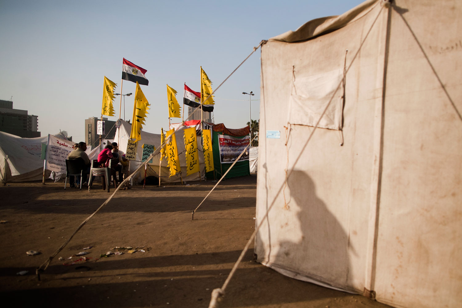 The shadow of a man can be seen on a tent as others meet in the background. The tent city of Tahrir has decreased in size over the past month.