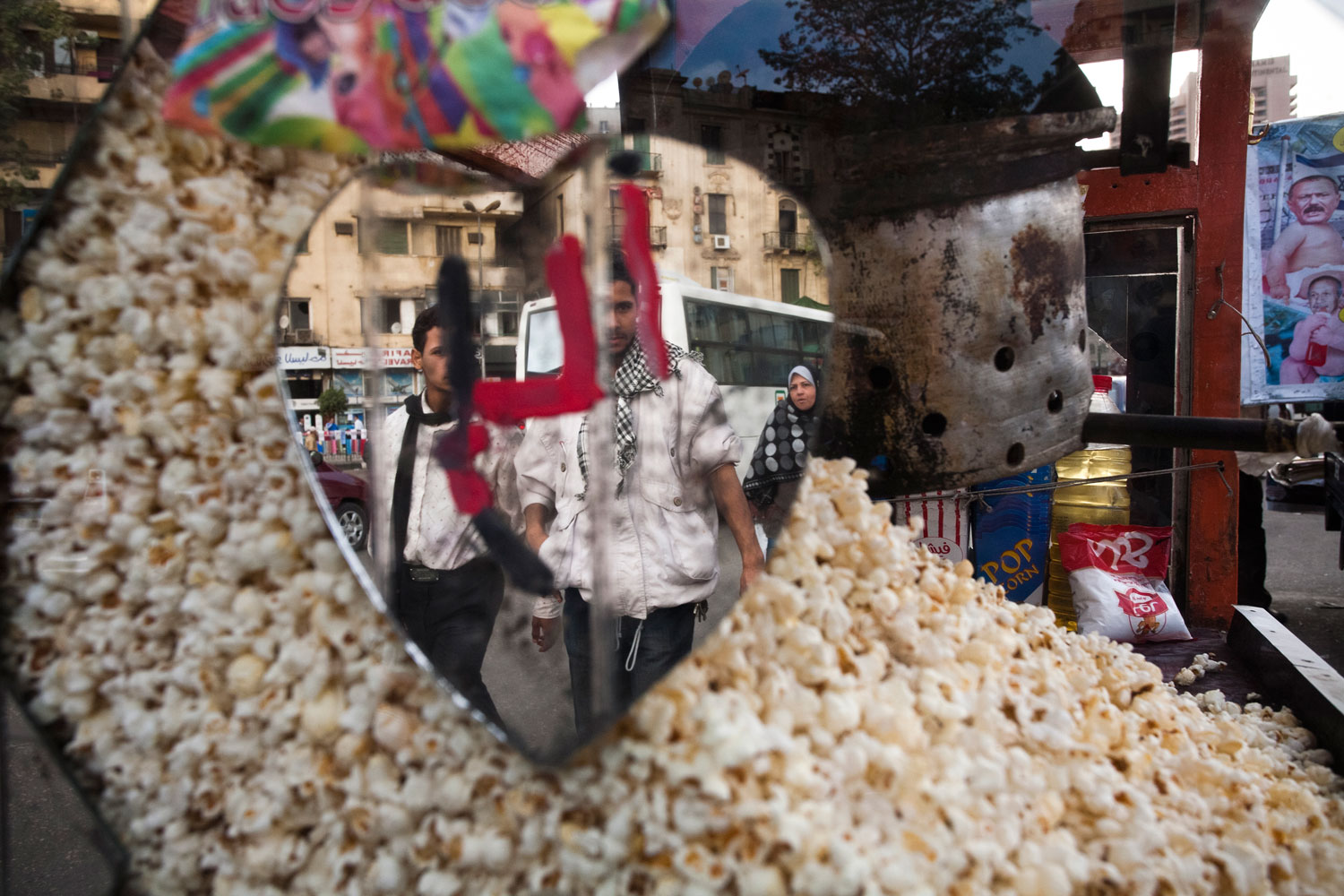 Two young Egyptian men walk past a popcorn vendor in Tahrir Square.