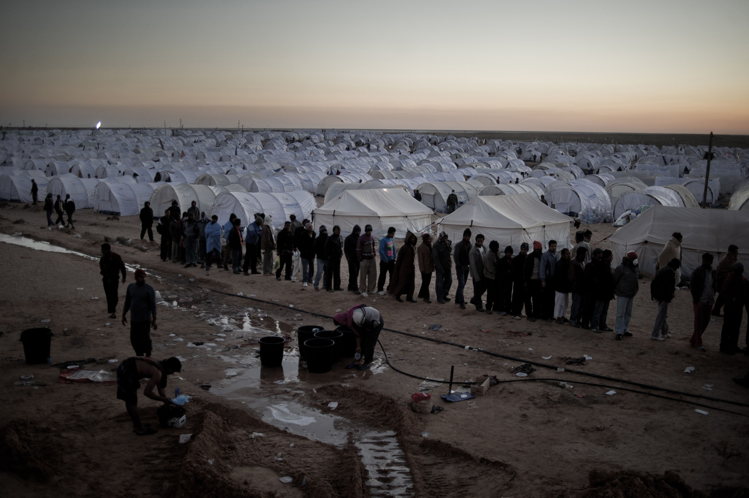 March 5, 2011. Men from Bangladesh, who used to work in Libya but recently fled due to unrest there, wash at a refugee camp after crossing the Tunisia-Libyan border.