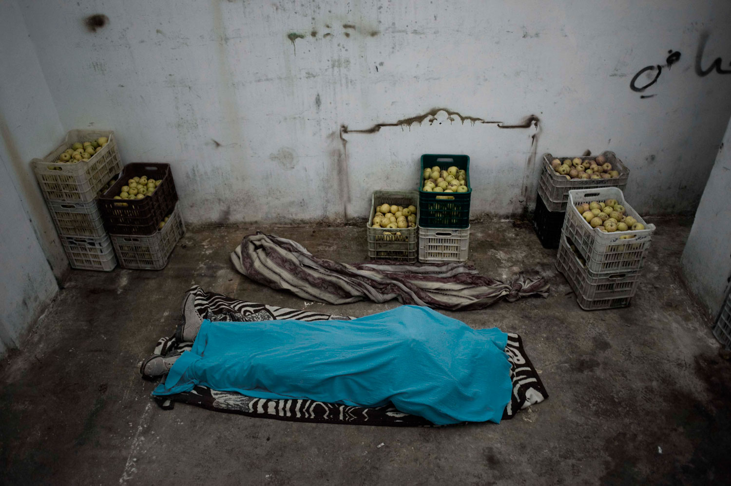 Feb. 9, 2012. The dead body of a Free Syrian Army fighter lies in an storage refrigerator in al-Qsair.
