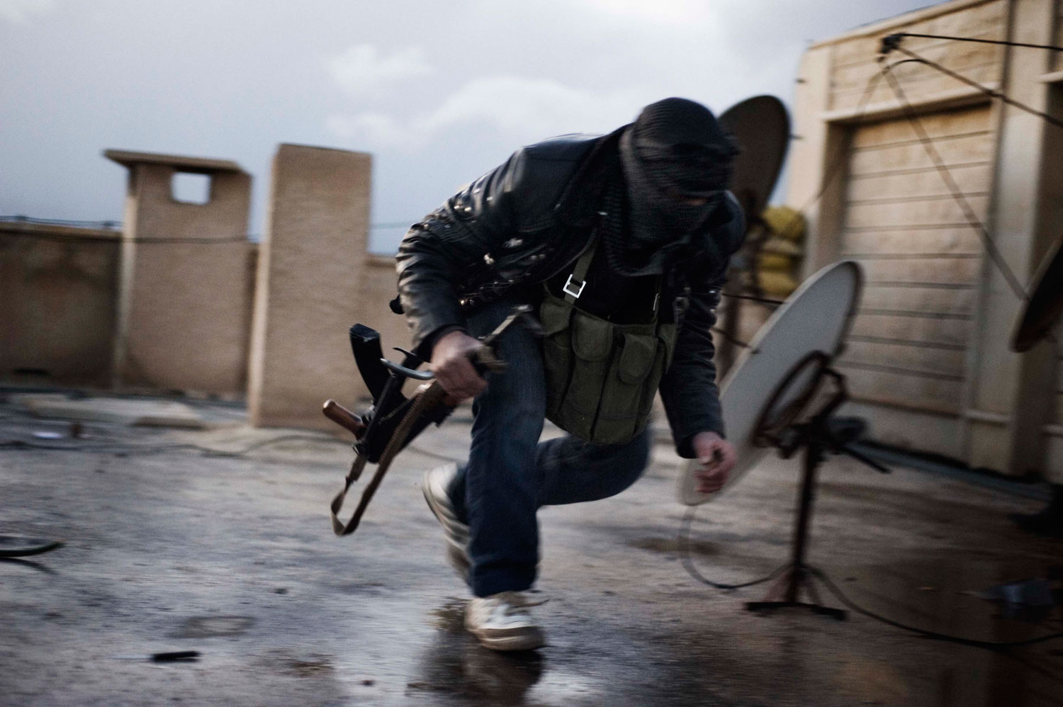 Feb. 10, 2012. A member of the Free Syrian Army takes cover from Syrian Army snipers on the roof of the former police station in al-Qsair.