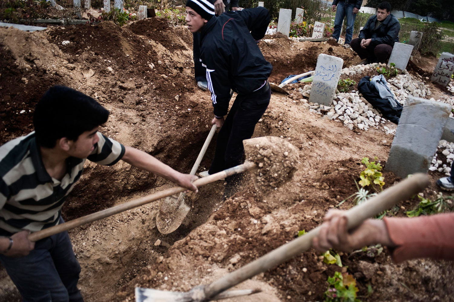 Feb. 14, 2012. A Syrian man (center) digs the grave for his father who, along with two other men, was kidnapped, then killed by the shabiha, in al-Qsair.