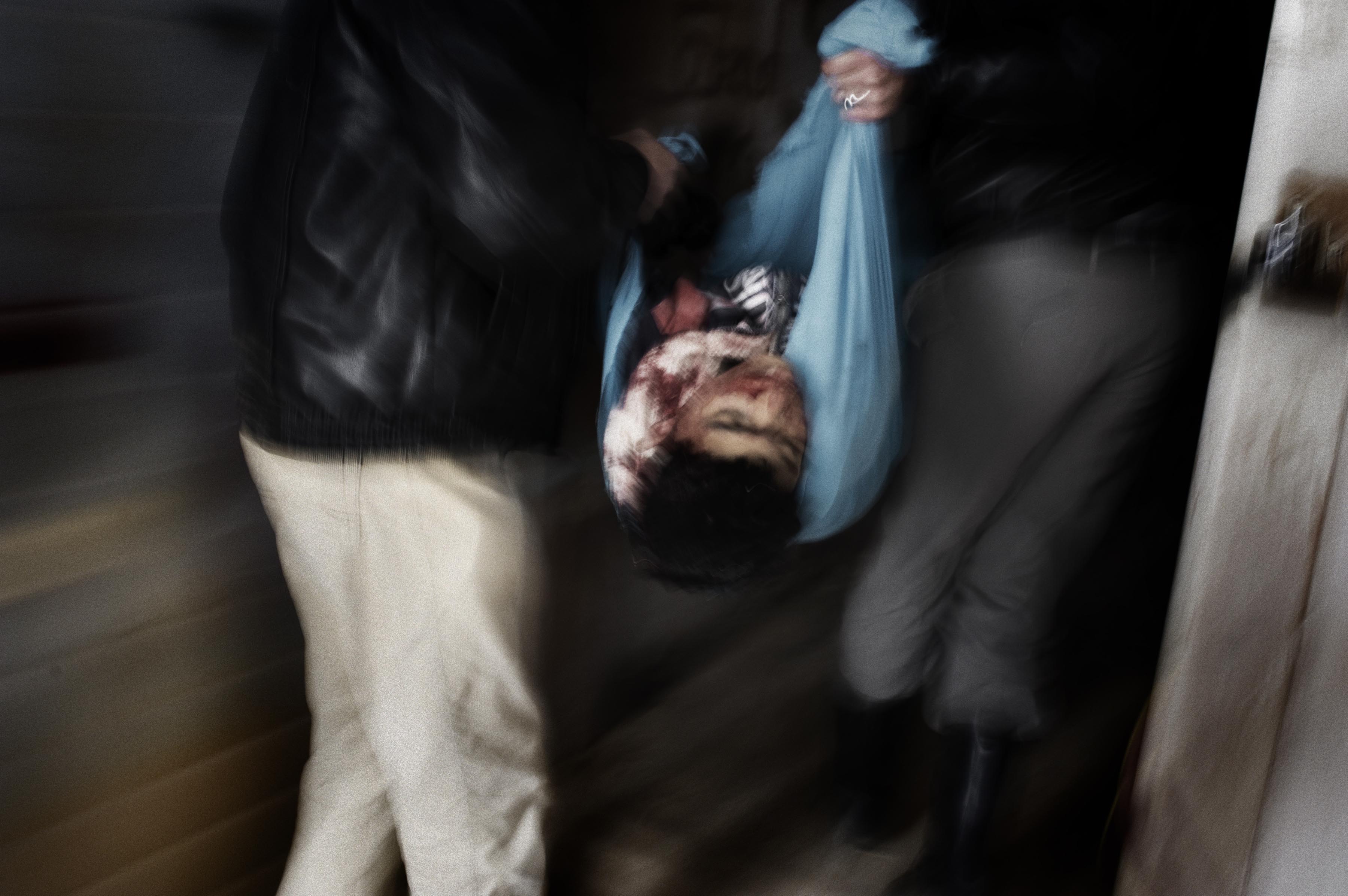 Feb. 20, 2012. Two Syrian men carry the body of a child who has been killed by an Al Assad army mortar in Homs Province.