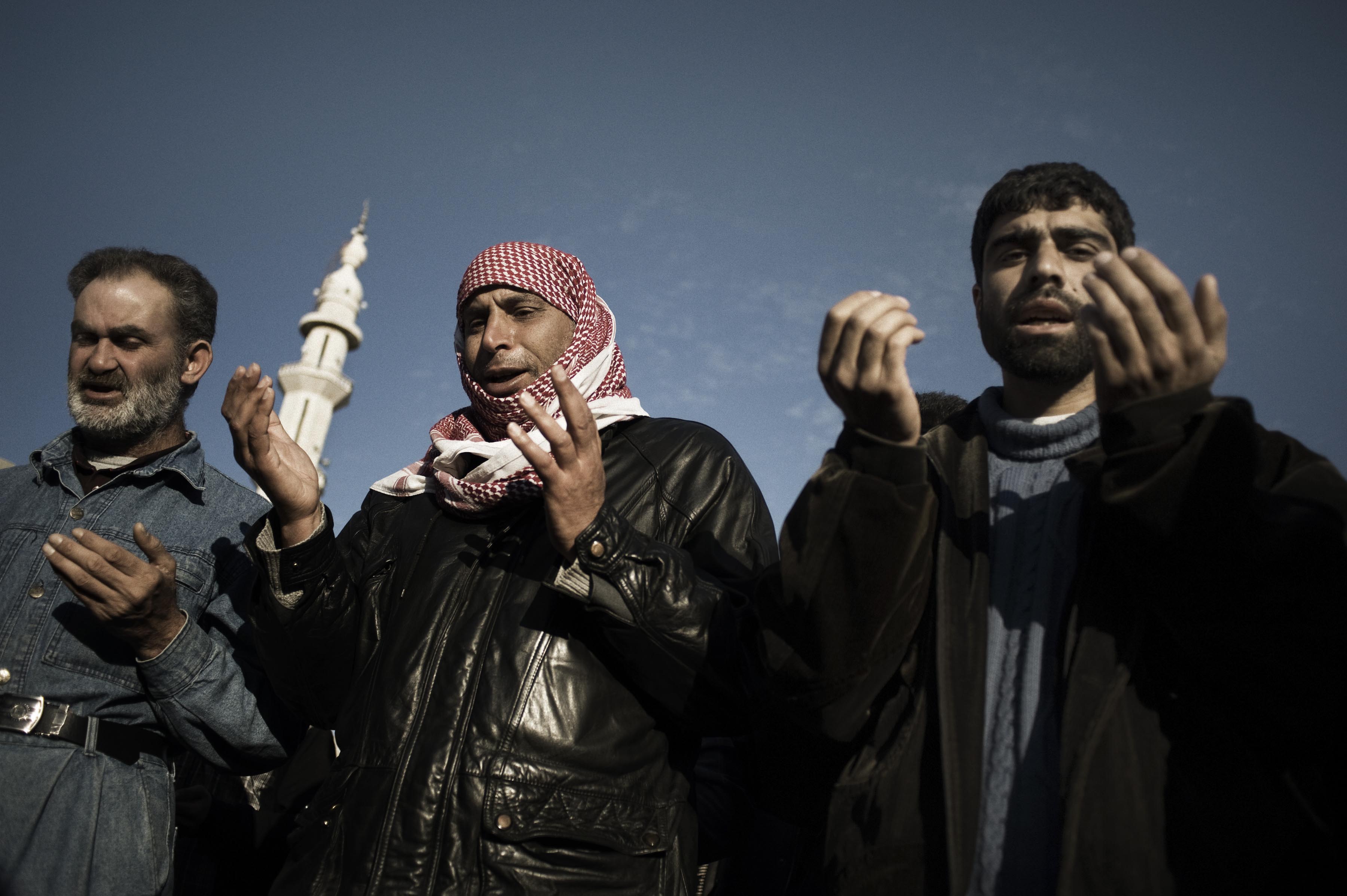 Feb. 20, 2012. Three Muslims pray among hundreds of people attending the funeral of five people killed by a mortar attack launched by Al Assad forces, in Homs Province.