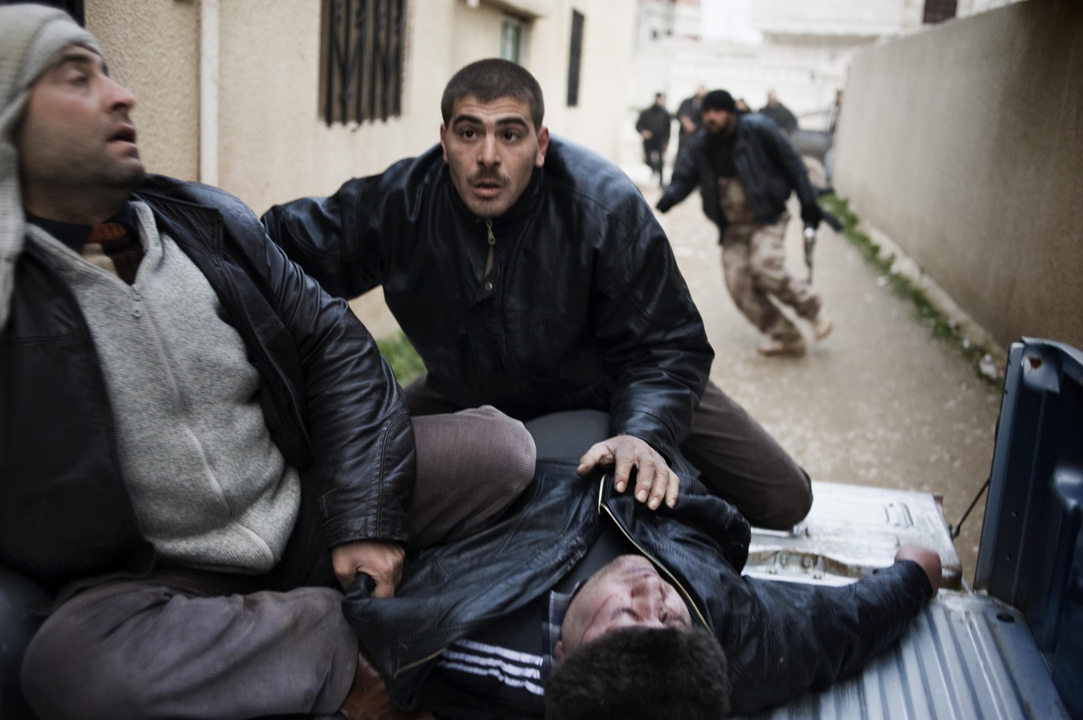 Feb. 22, 2012. Syrian men take a heavily wounded man into a house used as a hospital in Homs Province.