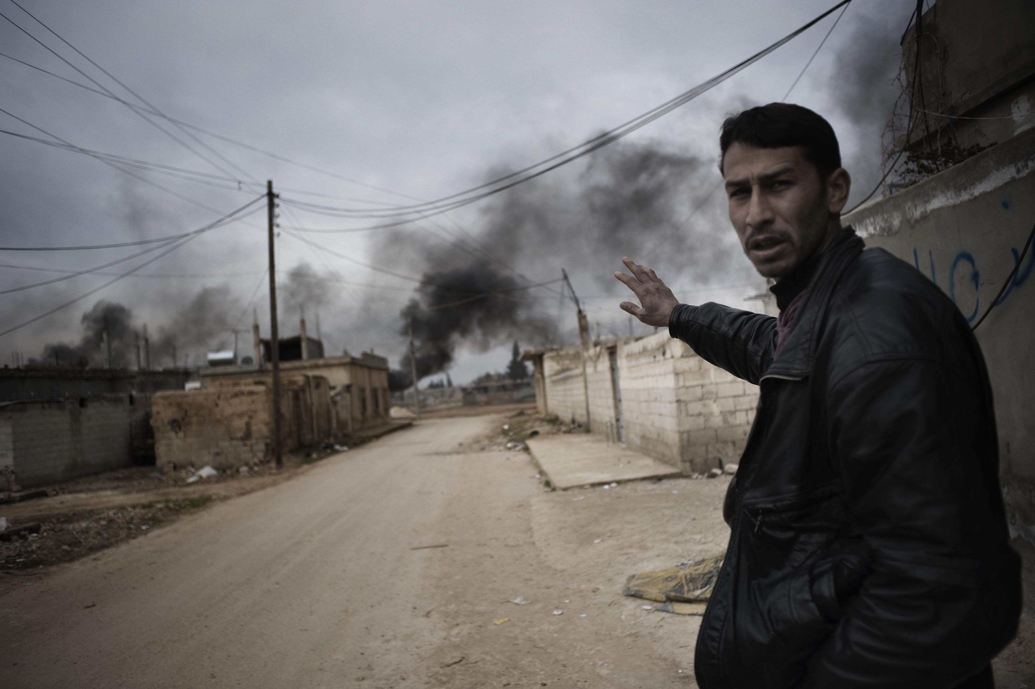 Feb. 23, 2012. A Syrian civilian shows the smoke of burning tires in a street close to combats between Free Syrian Army and Al Assad forces in al-Qsair.