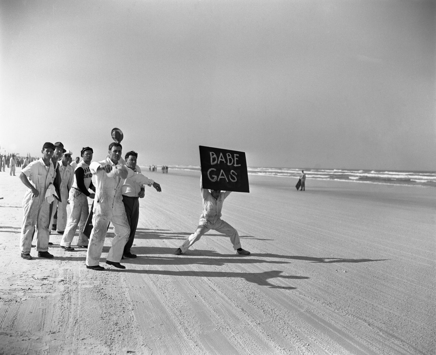 Spectators on the sidelines during the Daytona 200 in Daytona Beach, Florida, March 1948. One man holds up a sign reading 'Babe Gas'.