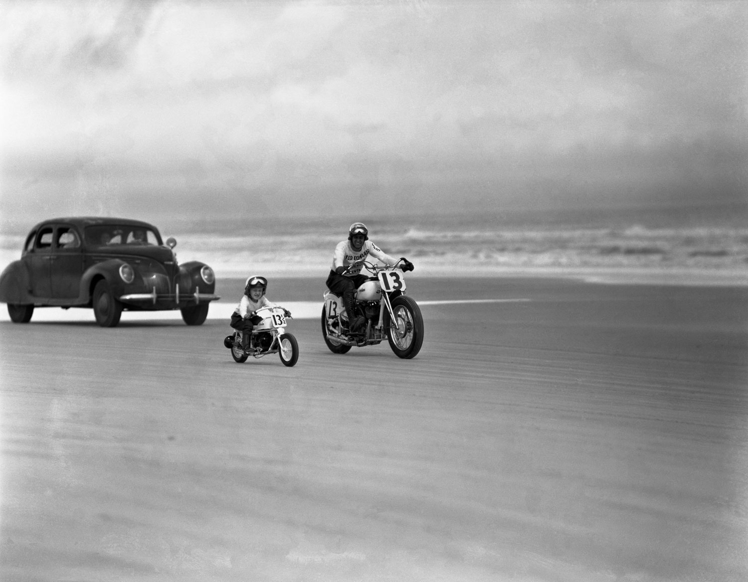 On matching full-size and miniature Indian motorcycles, a man and a boy ride along the beach, Daytona Beach, Florida, March 1948.