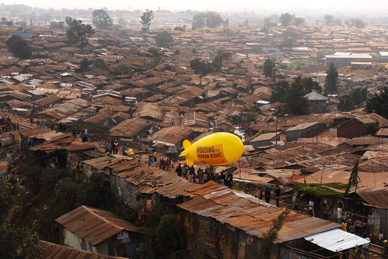 March 24, 2012. Members of Amnesty International carry a hot air balloon with text that reads 'Housing is a Human right' through the Kibera slum in Nairobi.