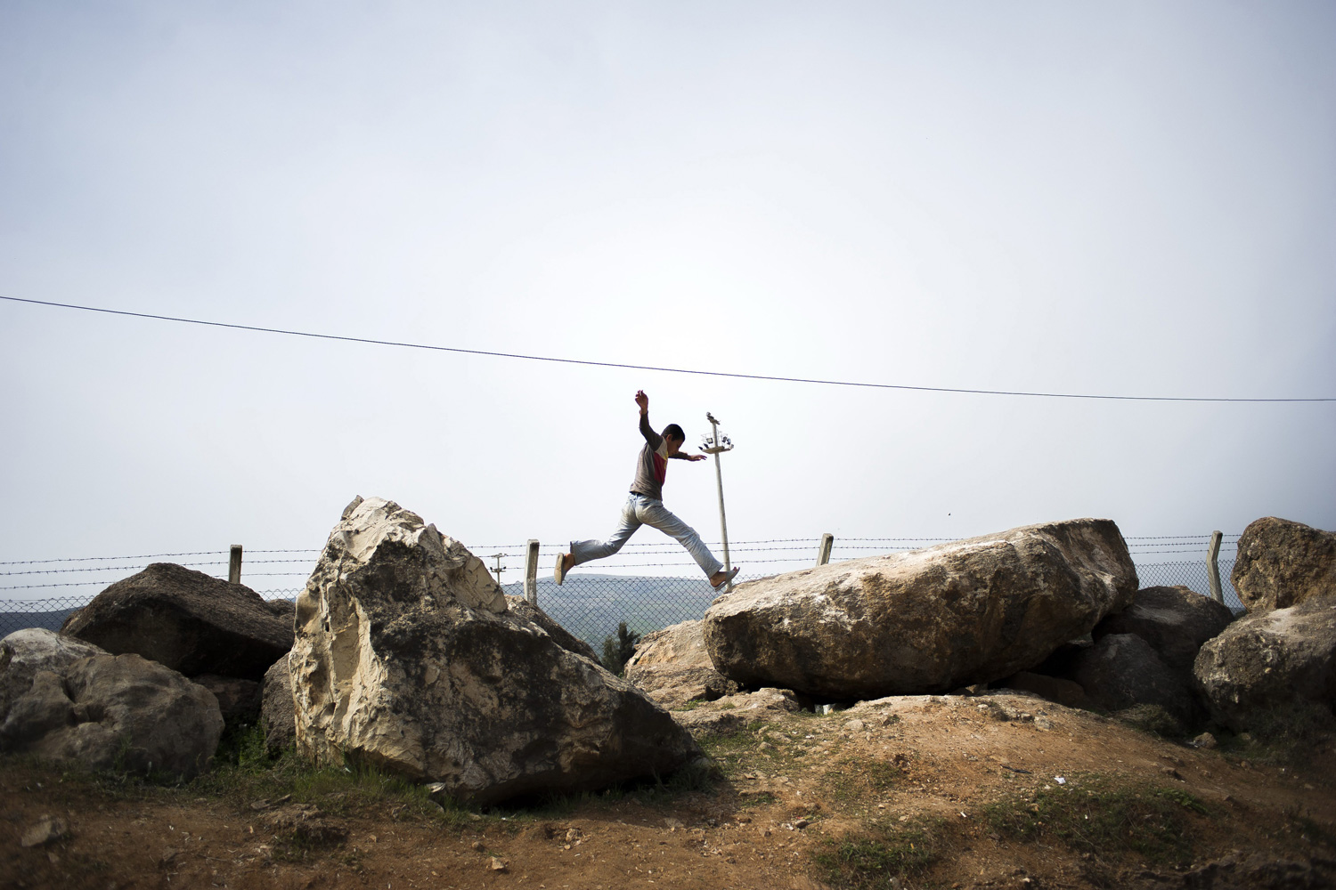 March 25, 2012. A Syrian refugee is seen leaping from rock to rock at the Reyhanli refugees camp in Turkey.