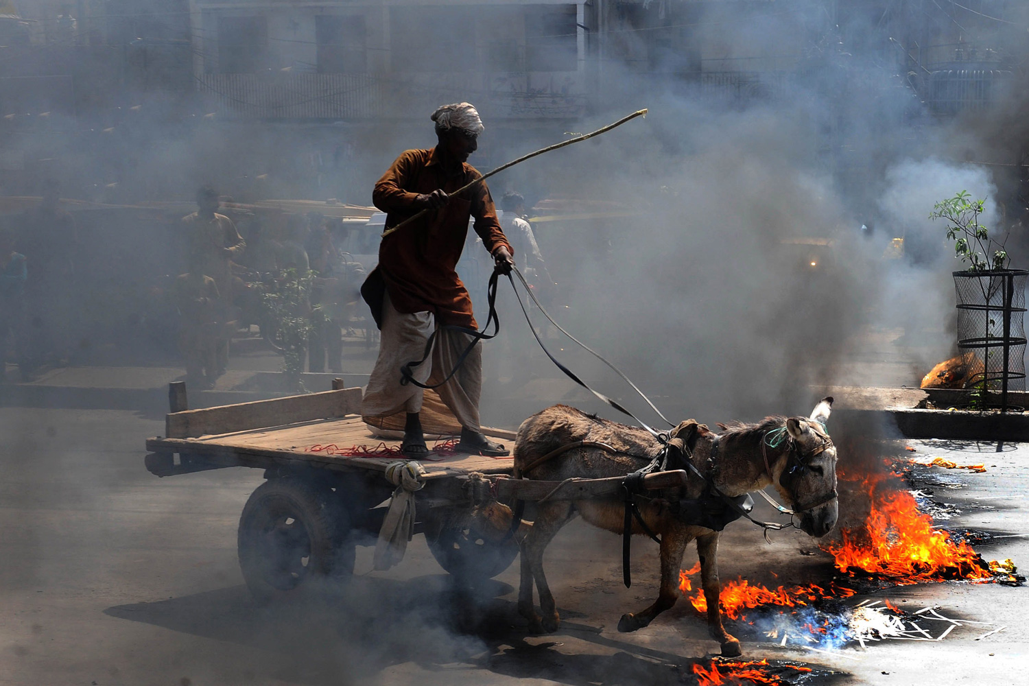 March 28, 2012. A Pakistani man rides his donkey cart on burning tires during a protest rally in Lahore, Pakistan, against widespread electricity shortages in the country.