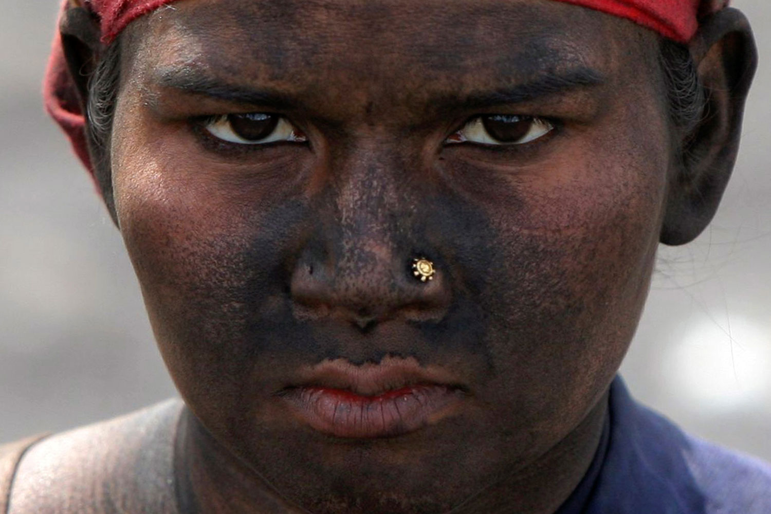 March 23, 2012. A female laborer looks on as she takes a break at a coal yard on the outskirts of Jammu, India.