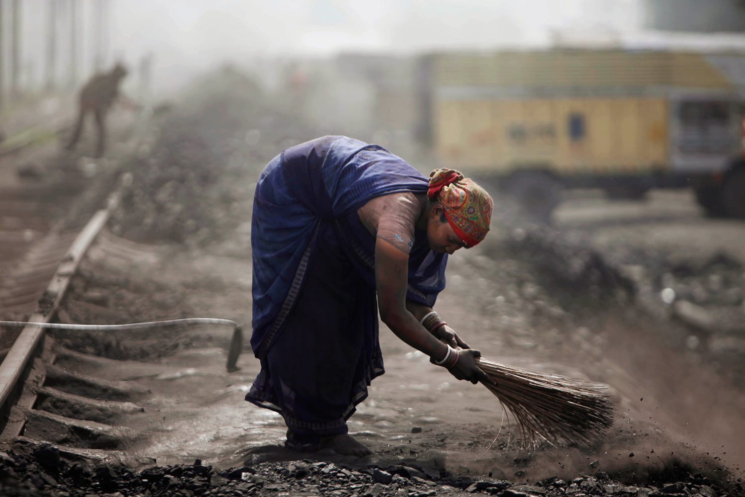 March 23, 2012. An Indian woman cleans the path near a coal depot on the outskirts of Jammu, India.