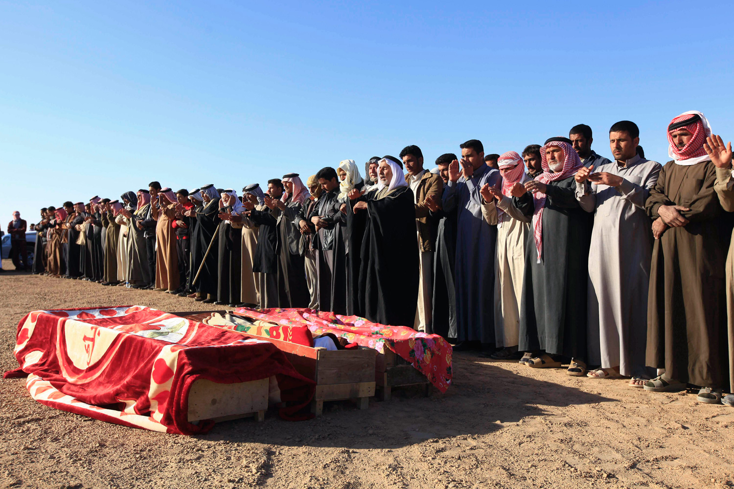 March 5, 2012. Mourners pray over the coffins of security forces killed in an attack in Haditha, Iraq, at their funeral in Fallujah.