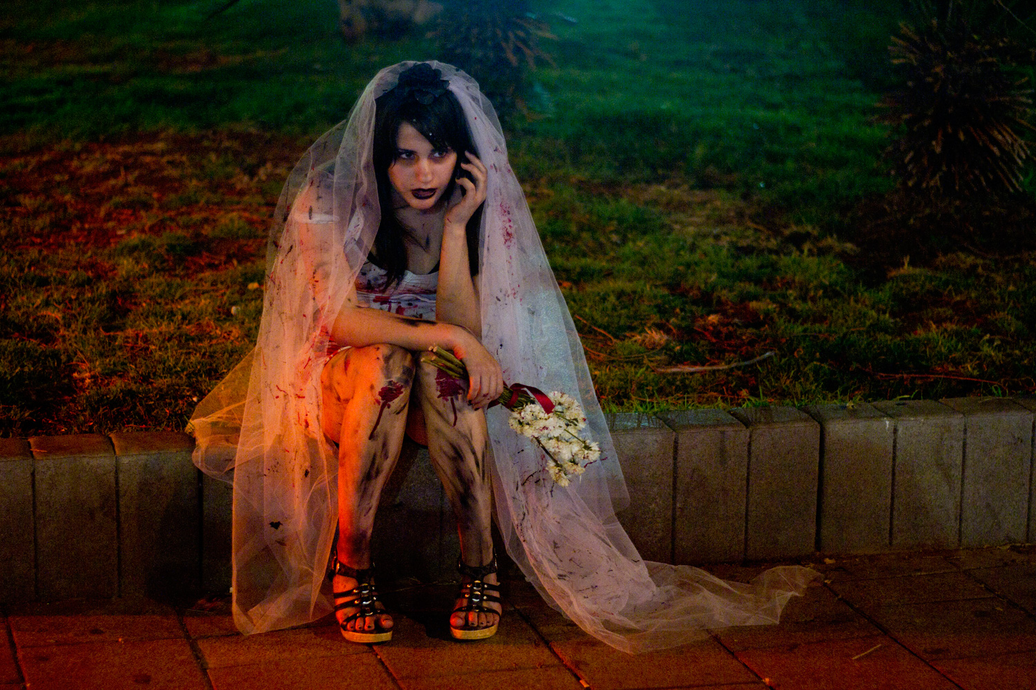 March 6, 2012. A woman wearing zombie make-up and a wedding dress speaks on the phone while waiting for a friend to join the 2012 Zombie Walk during the Purim festival in Tel Aviv.
