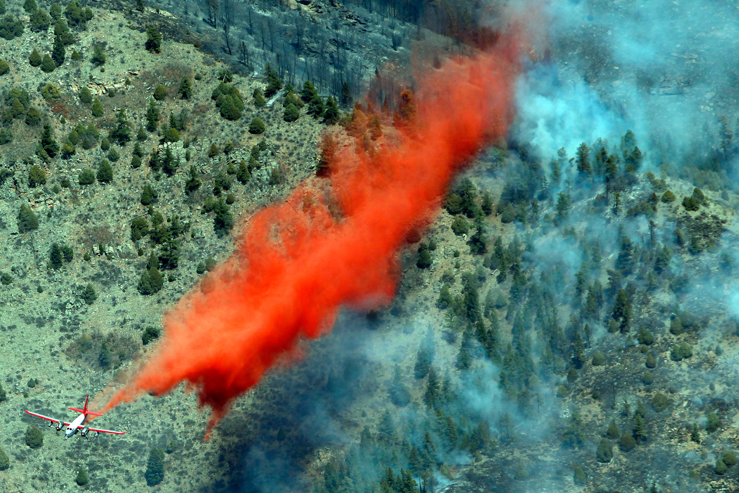 March 27, 2012. A trail of slurry is deposited by a bomber during a run over a smoldering ridge in the Lower North Fork Wildfire burning in the foothills community of Conifer, Colo.