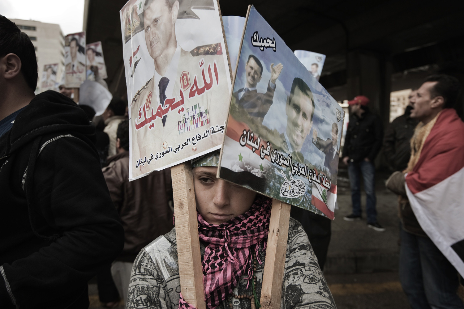 March 4, 2012. A young protester holds posters of Syrian President Bashar al-Assad reading  May God protect you  during a demonstration in support of the Syrian regime in Beirut.