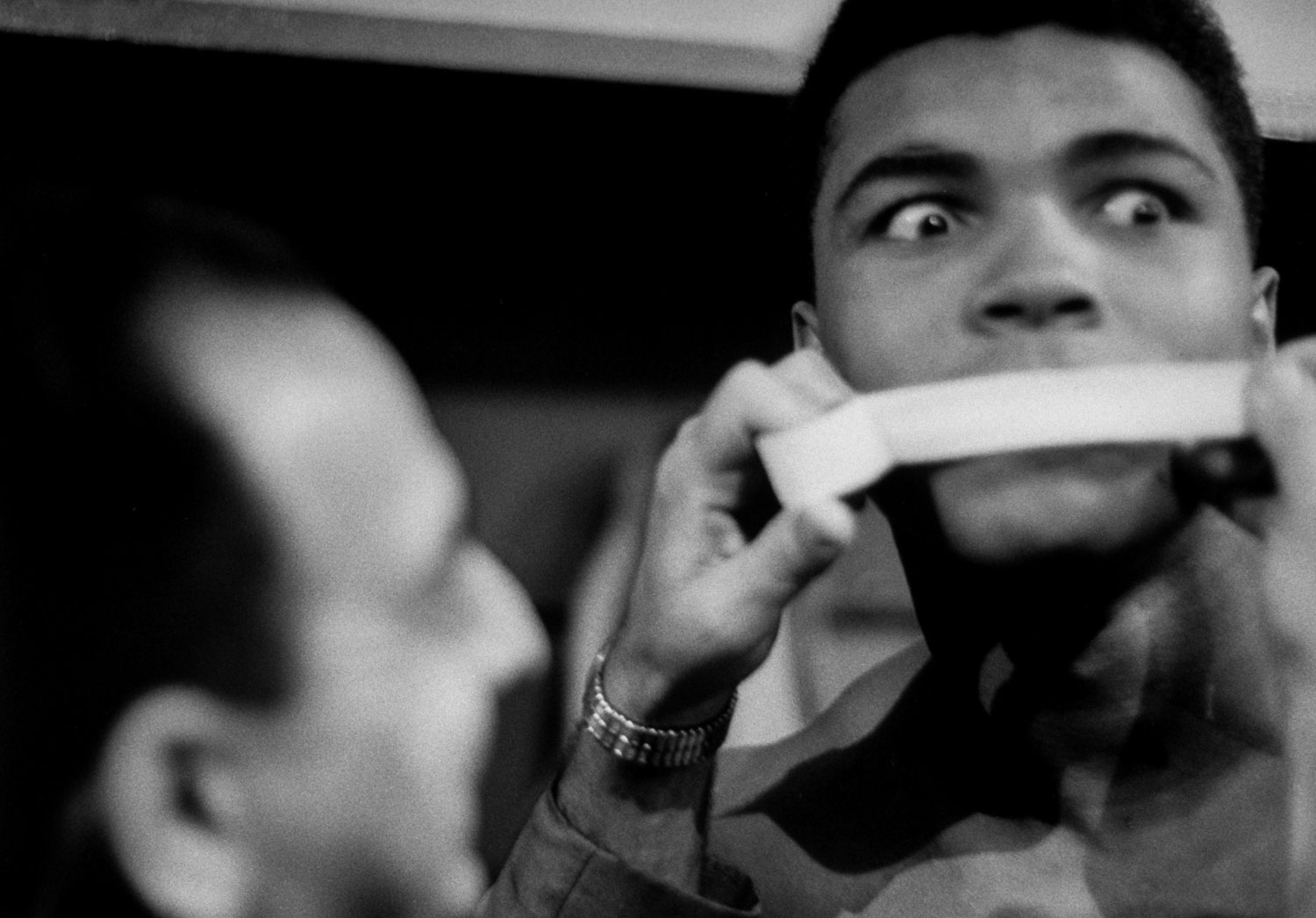Heavyweight contender Cassius Clay (later Muhammad Ali) getting his poetic mouth taped by trainer Angelo Dundee during his weigh-in before big fight with Doug Jones.