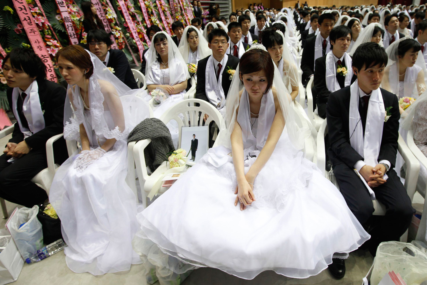 March 24, 2012. A bride, center, attends a mass wedding ceremony of the Unification Church as a portrait of her bridegroom, who could not attend the ceremony, is seen next to her on a chair in Gapyeong, about 60 km (37 miles) northeast of Seoul.