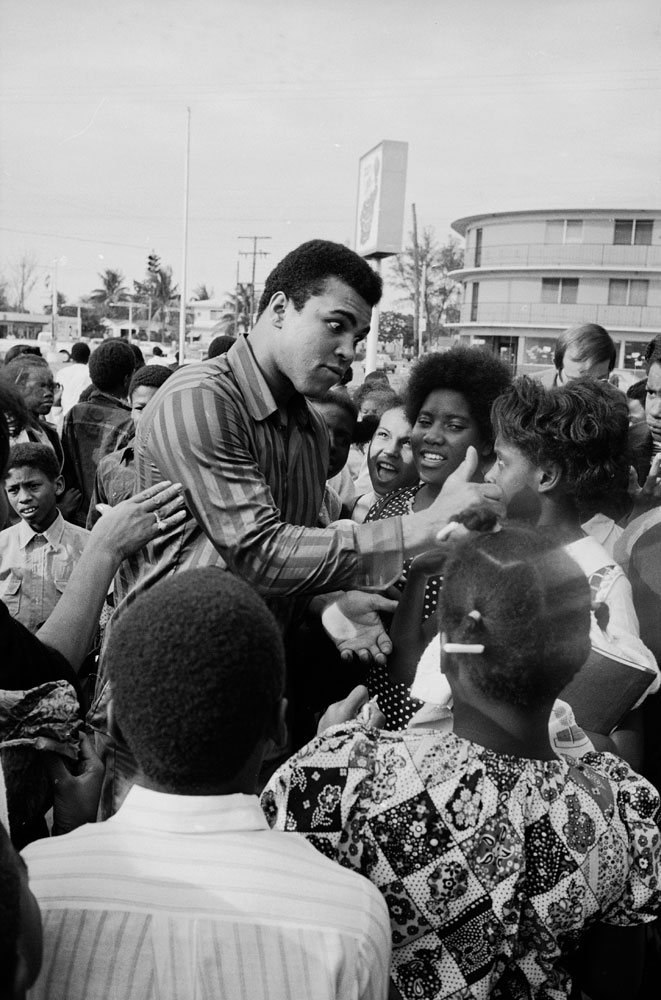 Boxer Muhammad Ali with fans in front of his "Champburger Restaurant" before bout with Joe Frazier.
