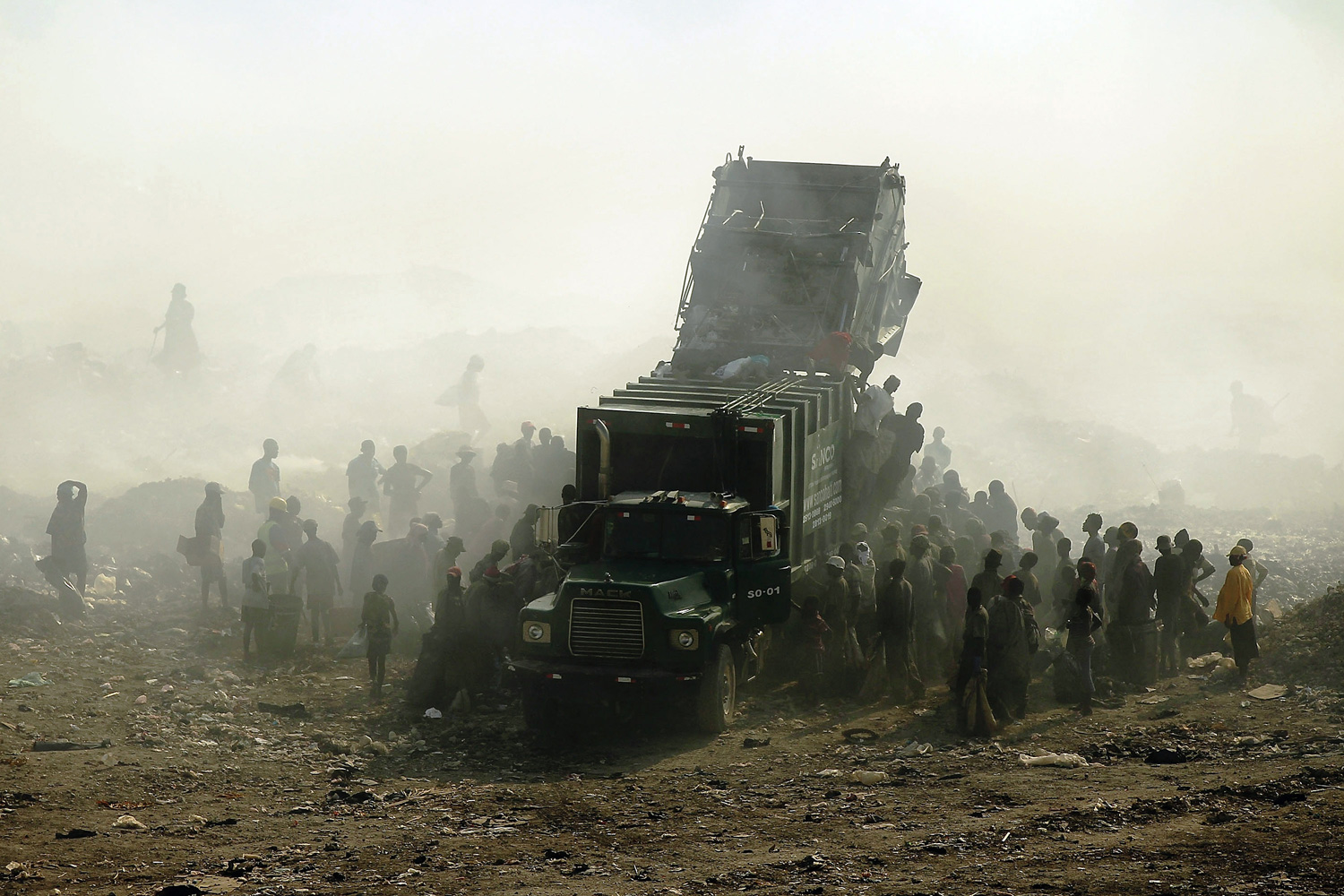 March 7, 2012. Children and adults scavenge for recyclables and other usable items around a garbage truck at the Trutier dump on the outskirts of Port-au-Prince, Haiti.