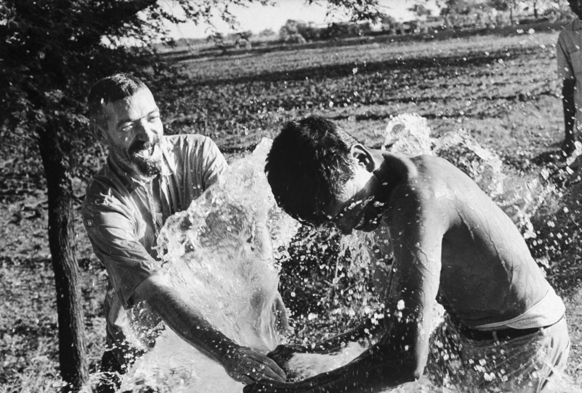 Missionary priest Vincent Ferrer (left) and assistant Mahadev (right) splash in water from a new well on a model farm in India in 1968.