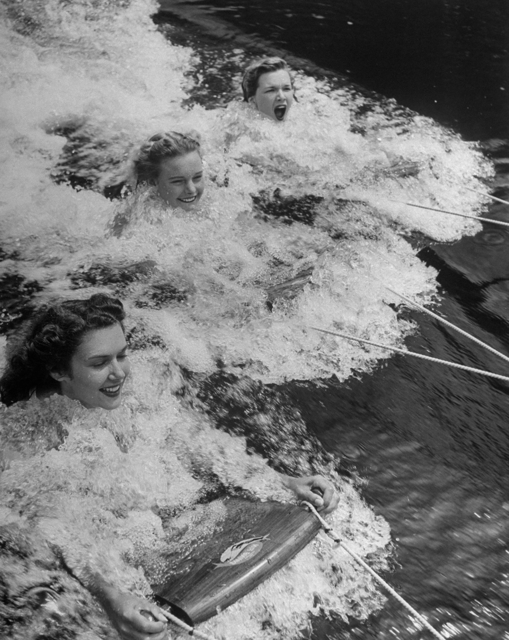 Women demonstrate the Porpoise Diving Fin, a streamlined 2-inch thick mahogany plank at the end of a tow rope, 1948.